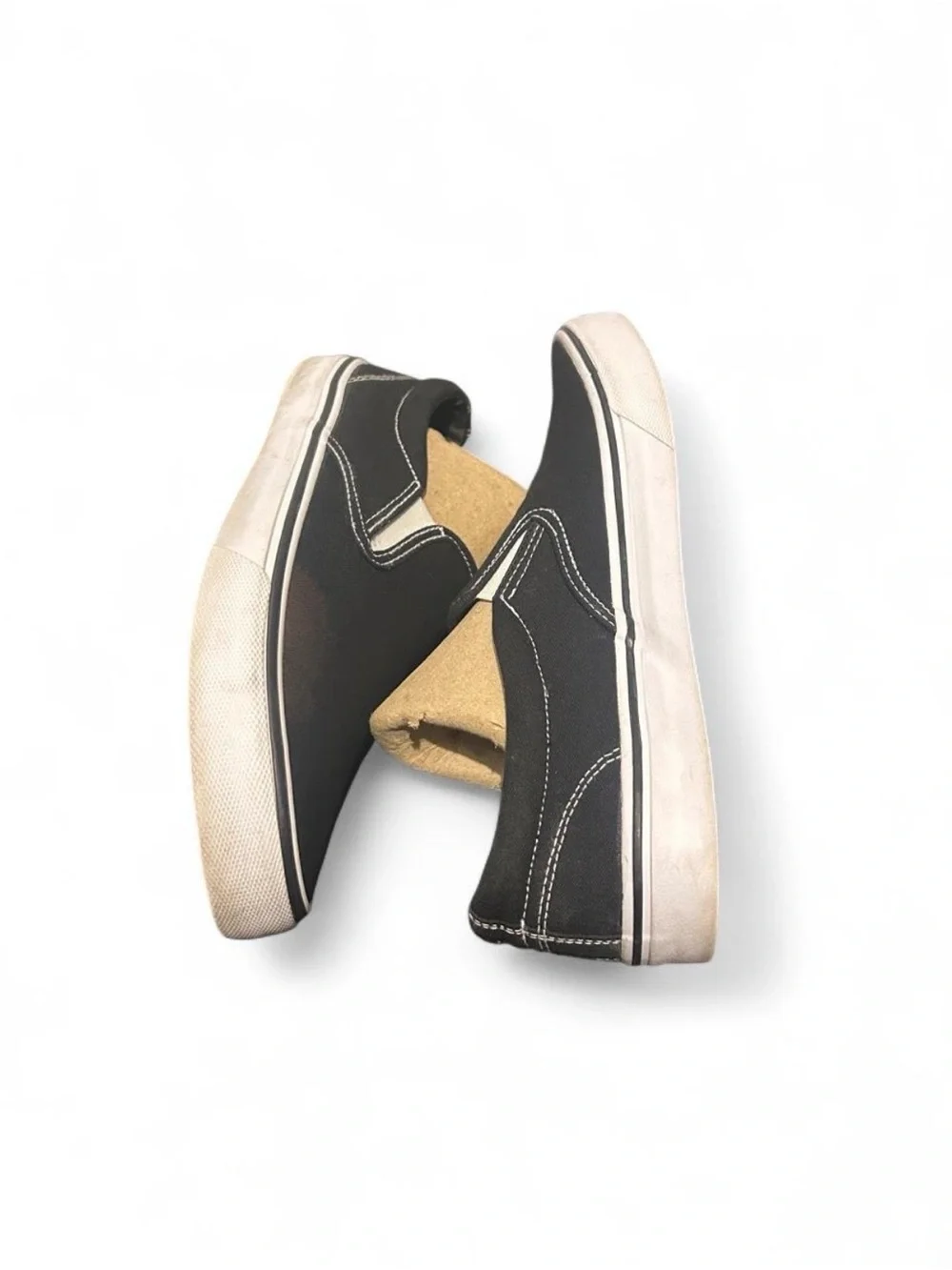 Black slip-on sneakers with white sole and white stitching